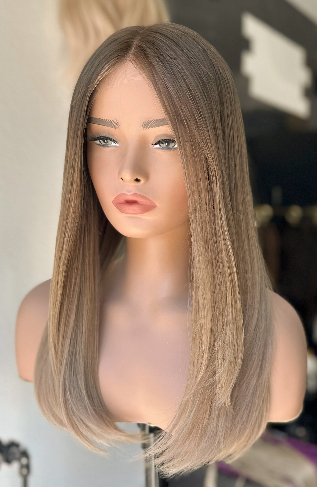 A small 20 inch wig on a mannequin head, with the mannequin having a neutral level 7 dark blonde base and cool level 9 blonde at the ends. The wig is presented in a lightweight texturized style.