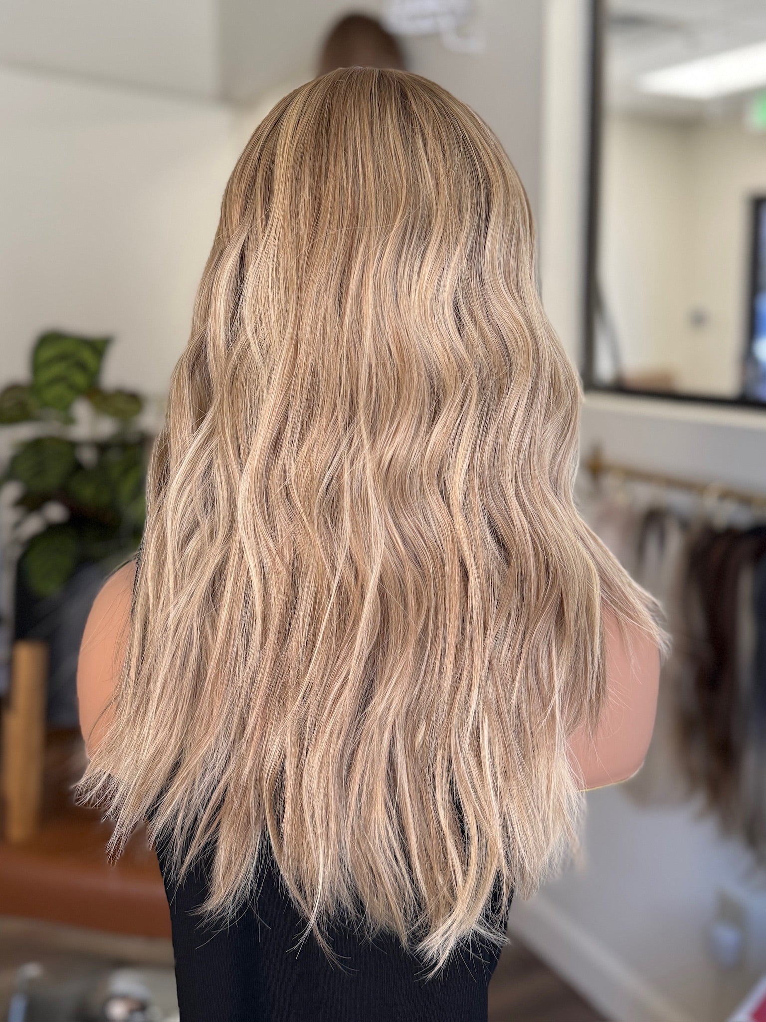 Blonde wig with highlights with long, wavy blonde hair in a salon setting for women with hairloss.