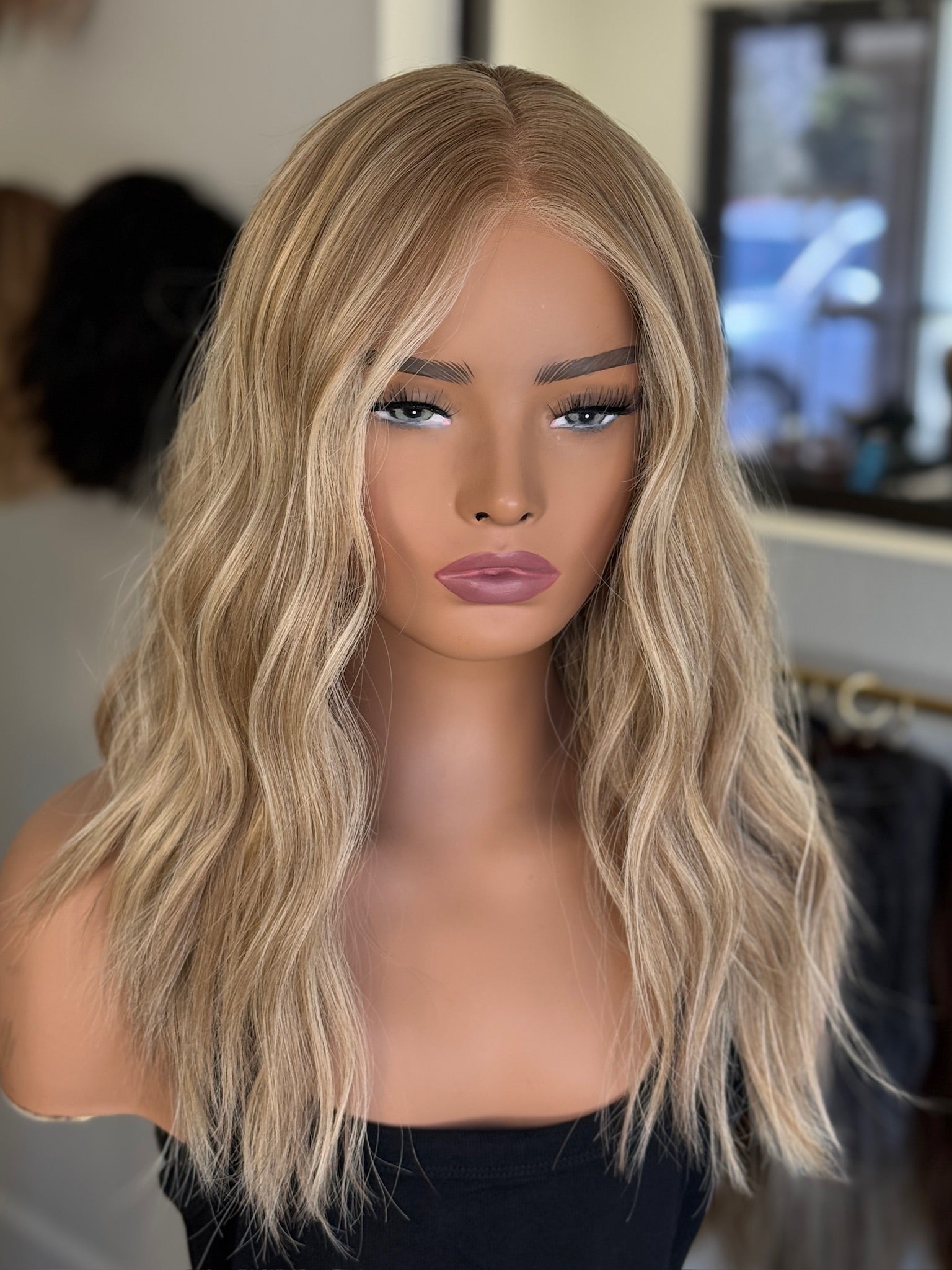 Rooted Blonde wig on a mannequin head with a blurred background