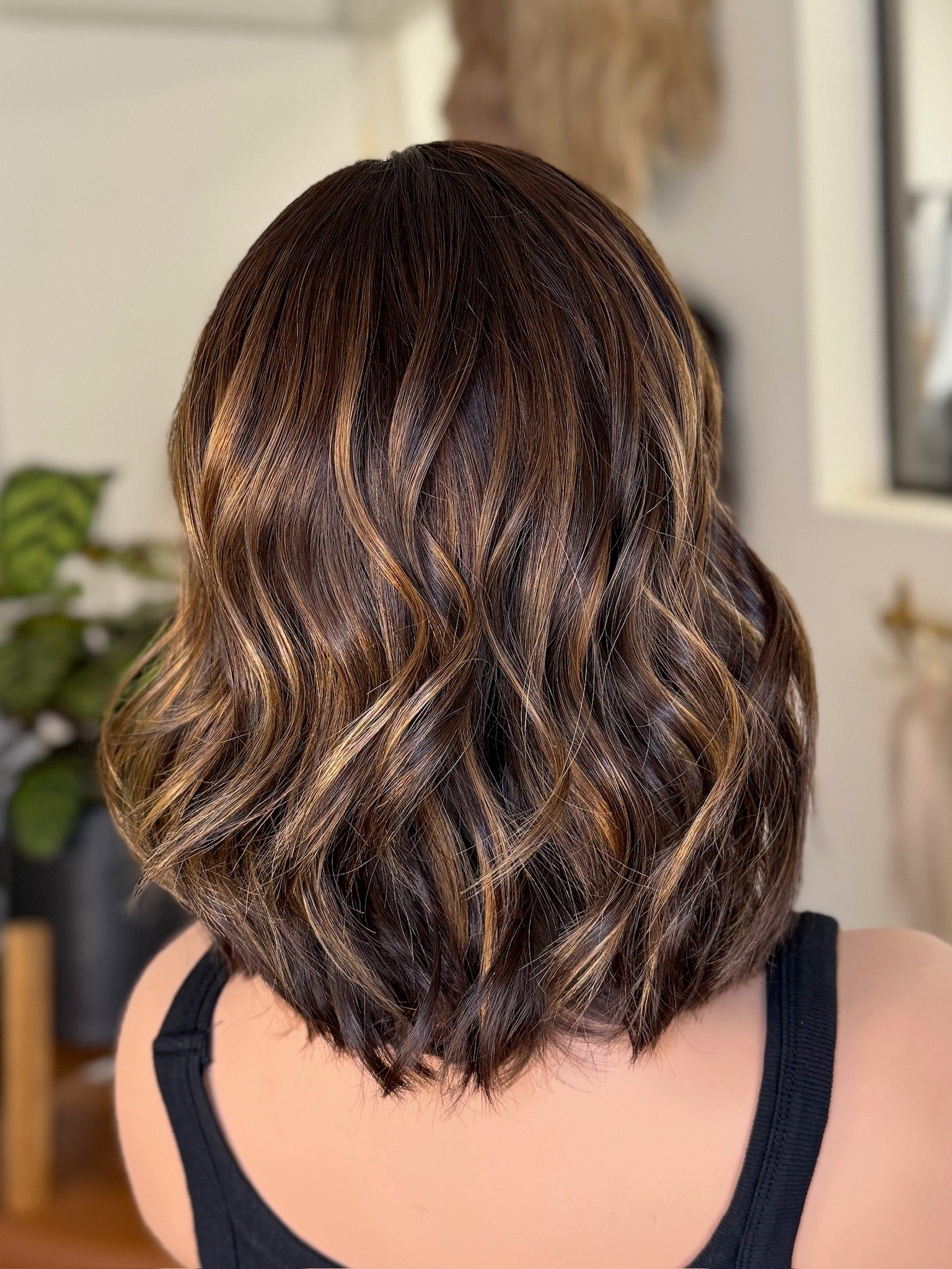 Back view of a Mannequin head with wavy brown wig in an indoor setting