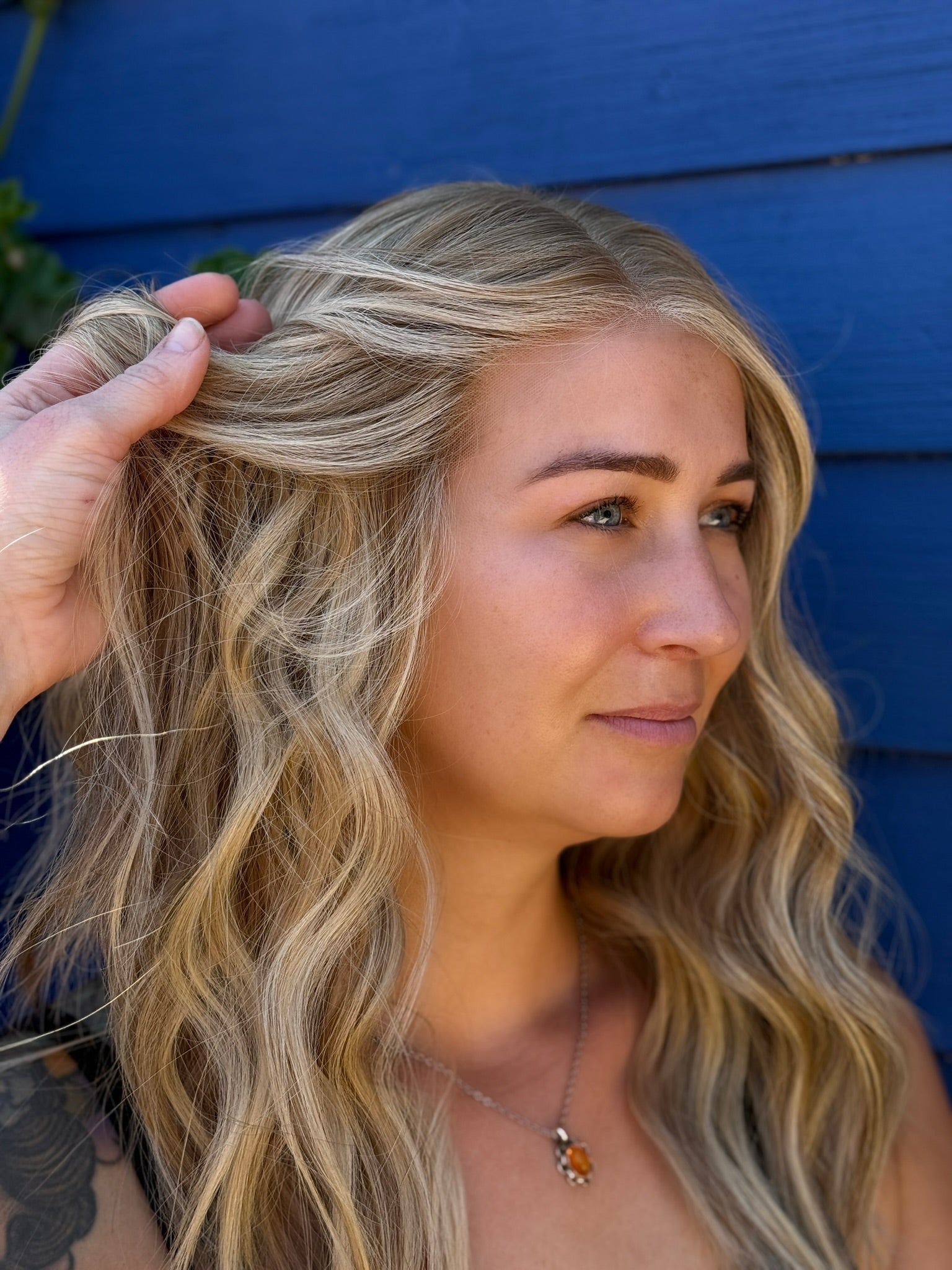 Woman with blonde hair being styled against a blue background