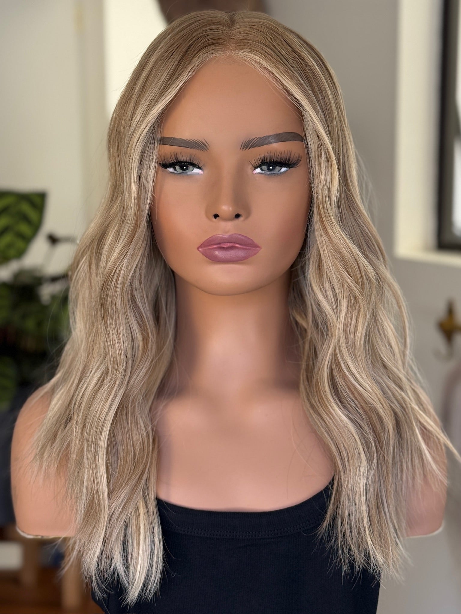 Mannequin head with a rooted blonde wig on a blurred indoor background