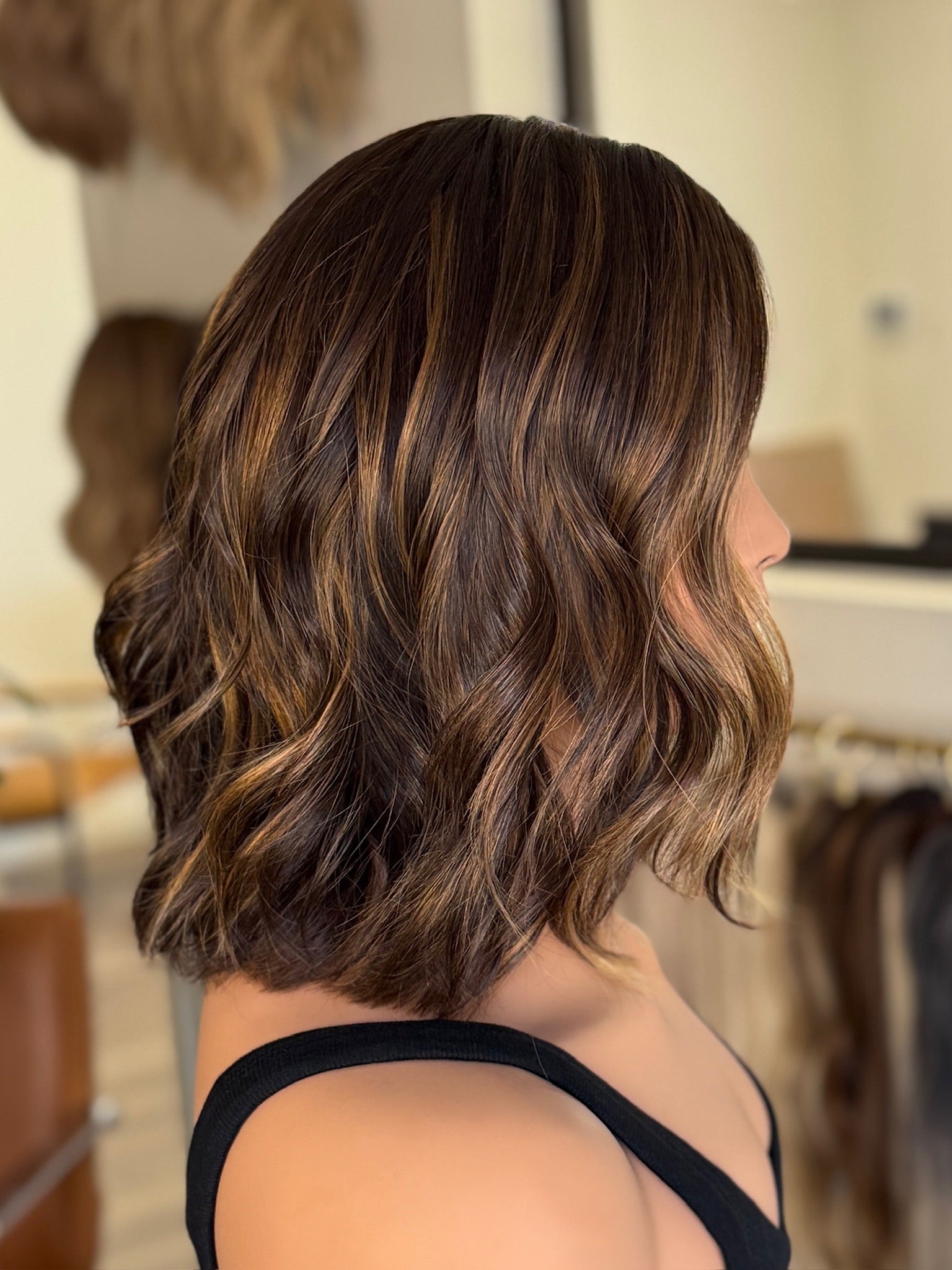 Mannequin head with wavy brown wig in a salon setting