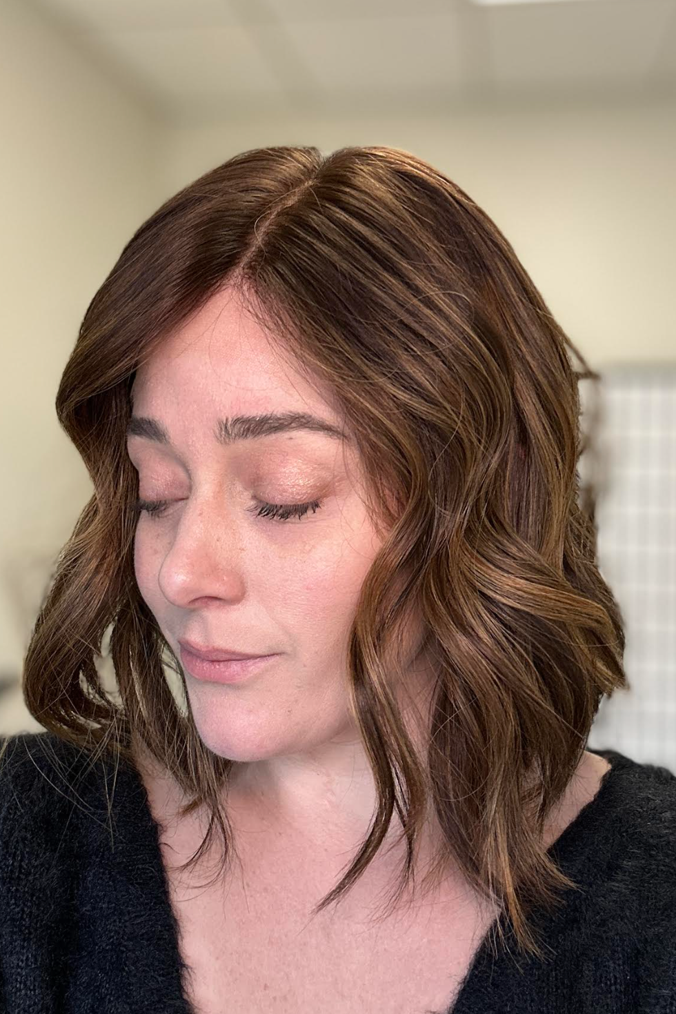 Woman with shoulder-length wavy wig in a neutral indoor setting